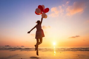Traumleben-Frau mit Luftballons am Meer
